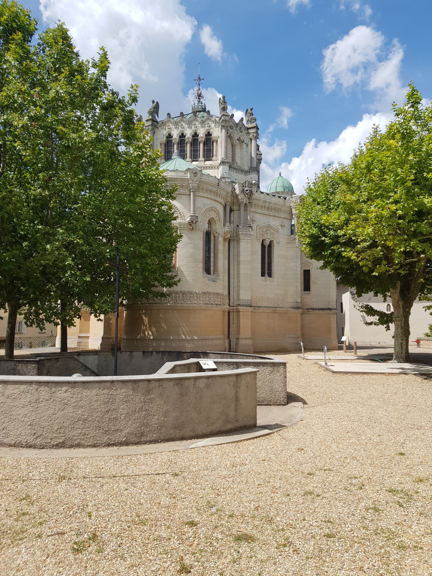 Place de village avec fontaine et arbres.