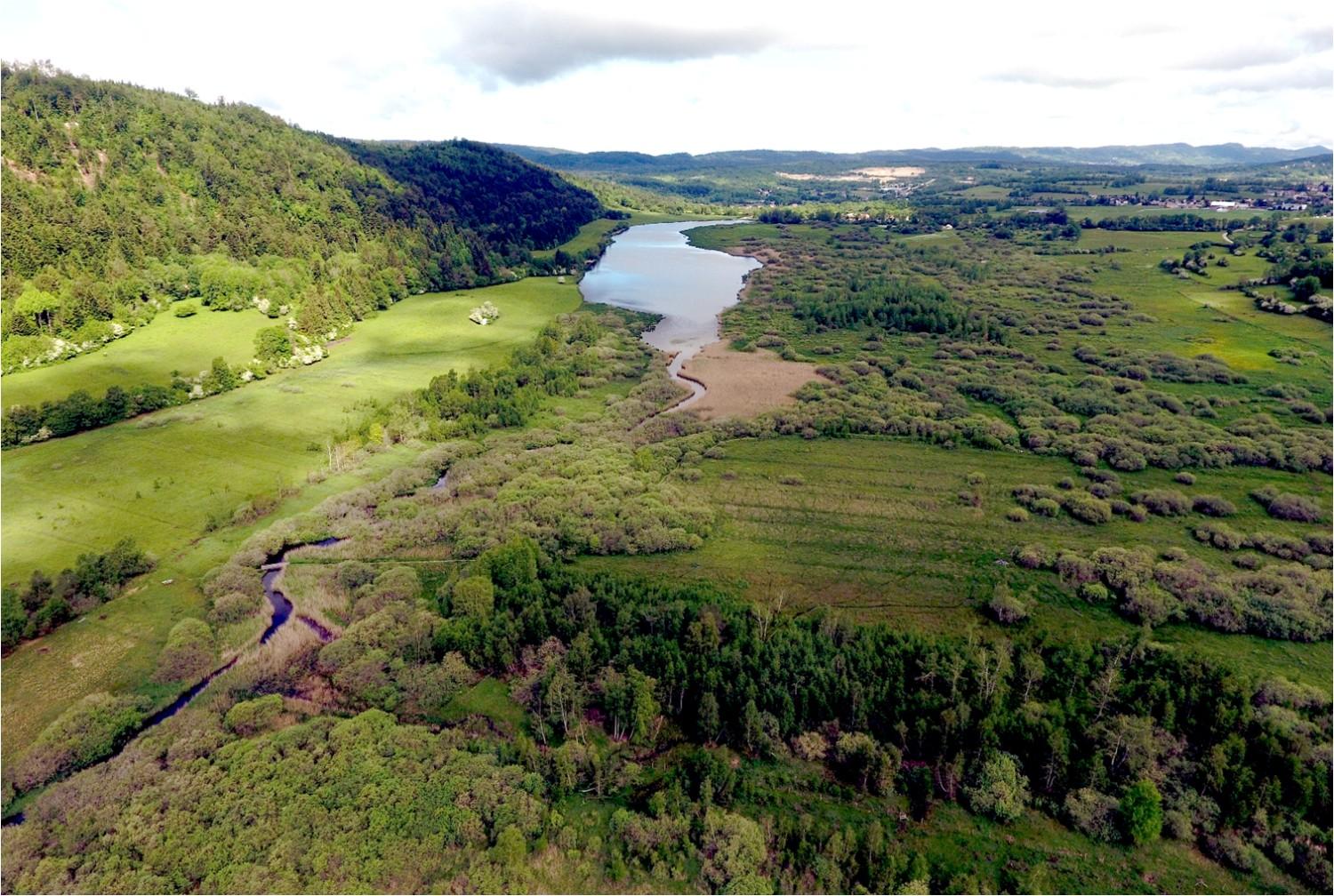 Vue panoramique d’une rivière dans un paysage vallonné.