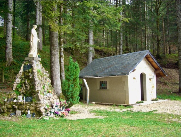 Petite maison blanche dans une clairière boisée.